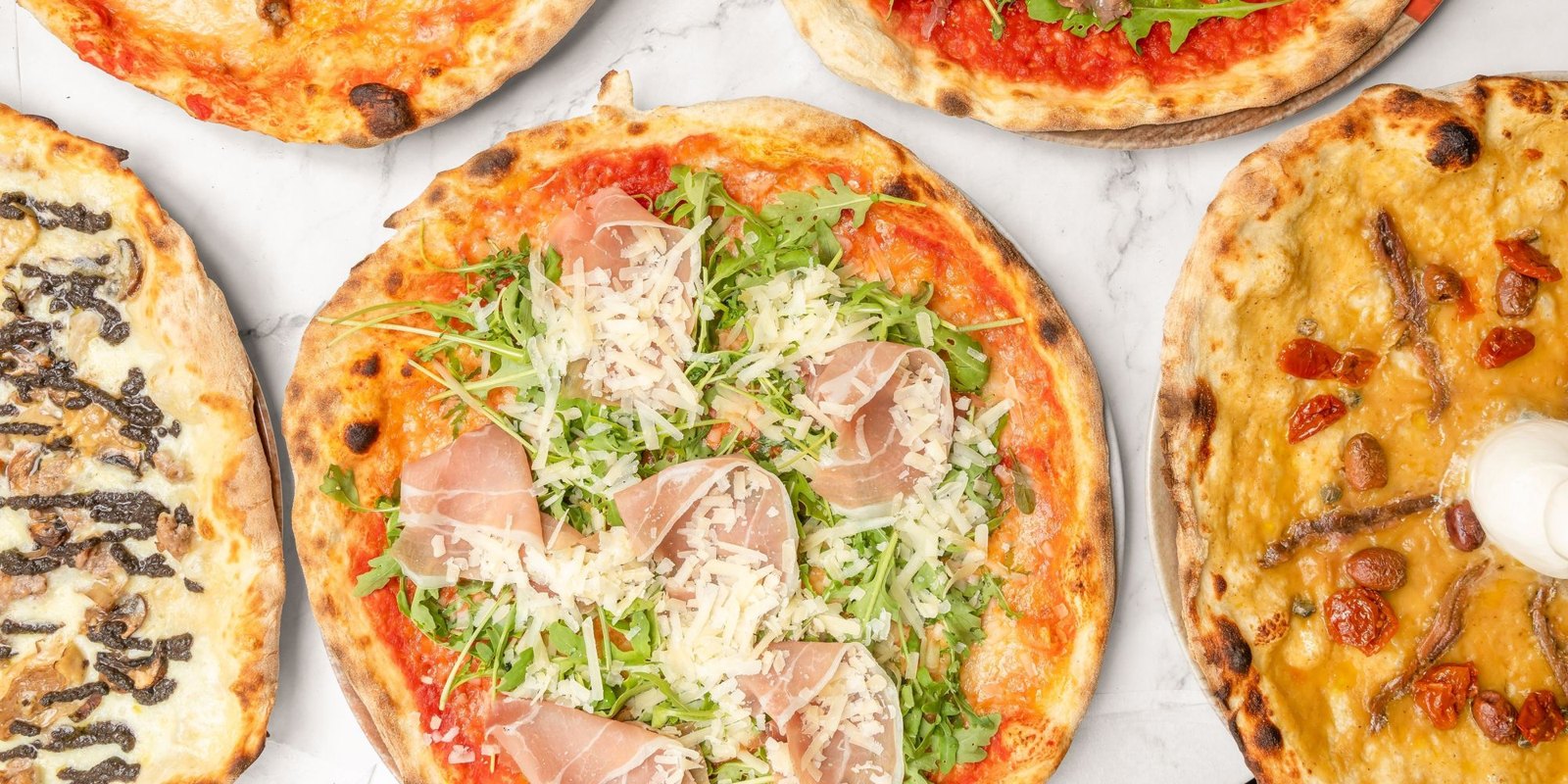 Pizzen von PIZZAMO mit verschiedenen Belägen auf hellem Marmor